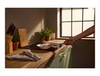 A person holding a copper frying pan on an induction hob in a kitchen.