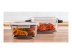 Glass food containers with roasted potatoes and chicken wings on a wooden table.