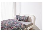 A bed with floral duvet cover and pillows in a bright room.