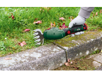 Trimmer de gazon manual verde tăind marginea unei căi de piatră.