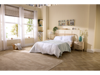 A light and airy bedroom features a wooden bed with white bedding, a beige rug, and a standing fan.