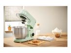 A mint green SilverCrest stand mixer with a whisk attachment, bowl, and baking ingredients.
