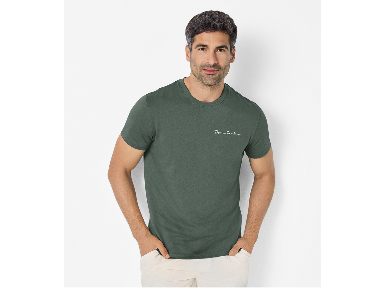 Bărbat în tricou verde ESMARA MEN cu inscripția „Thrive in the unknown” și pantaloni deschiși.