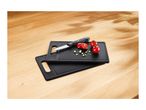 Two black cutting boards with a knife, tomatoes, and chopped chives on a wooden table.