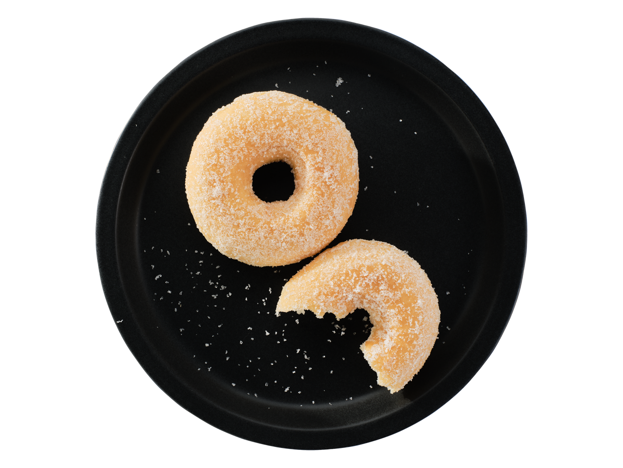 Două gogoși cu zahăr, una mușcată, pe o farfurie neagră.