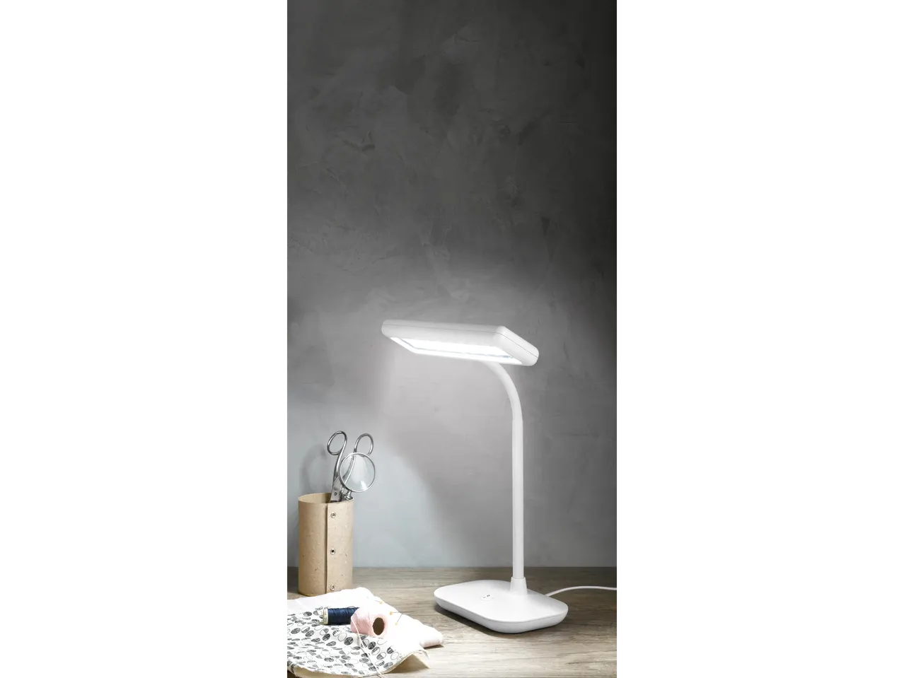 LIVARNO home LED stona lampa na drvenom stolu sa priborom za šivenje.