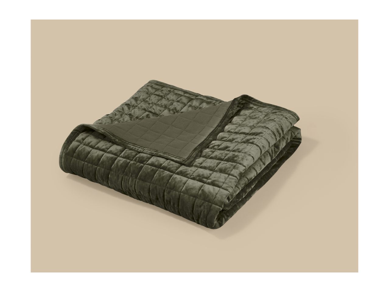 A folded olive green quilted velvet blanket on a beige background