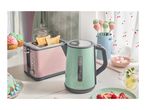 A pink toaster and a mint green kettle on a kitchen counter with various sweets.