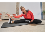 Woman in Crivit sweatshirt and sweatpants stretching on a yoga mat.