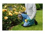 Person kneeling with Parkside knee pads, pruning shears, and gloves, tending to yellow roses.
