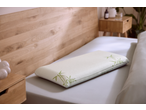 Memory foam pillow with bamboo print on a bed with wooden headboard and nightstand