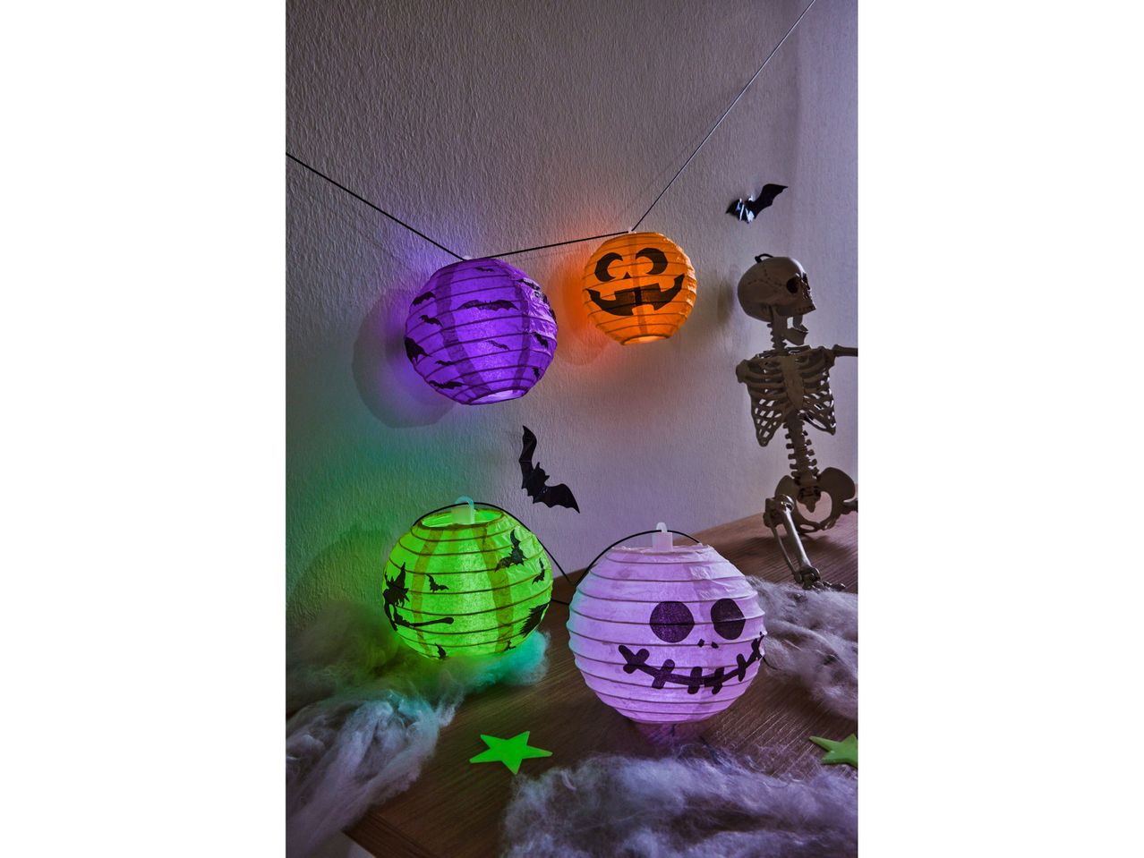 Halloween lanterns and skeleton decoration on a wooden surface with cobwebs.