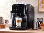 A SilverCrest coffee machine with a latte in a glass, a metal pitcher, and coffee beans.