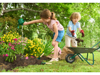 Dvoje djece vrtlare s kolicima i alatom, zalijevaju cvijeće i premještaju zemlju.