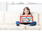 O fetiță zâmbitoare se uită la un laptop roșu cu tematică Paw Patrol pe canapea.