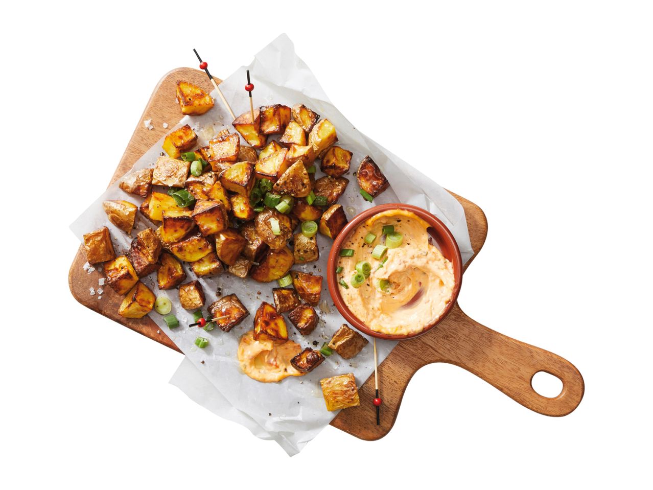 Roasted potatoes with green onions and a creamy dipping sauce on a wooden board.