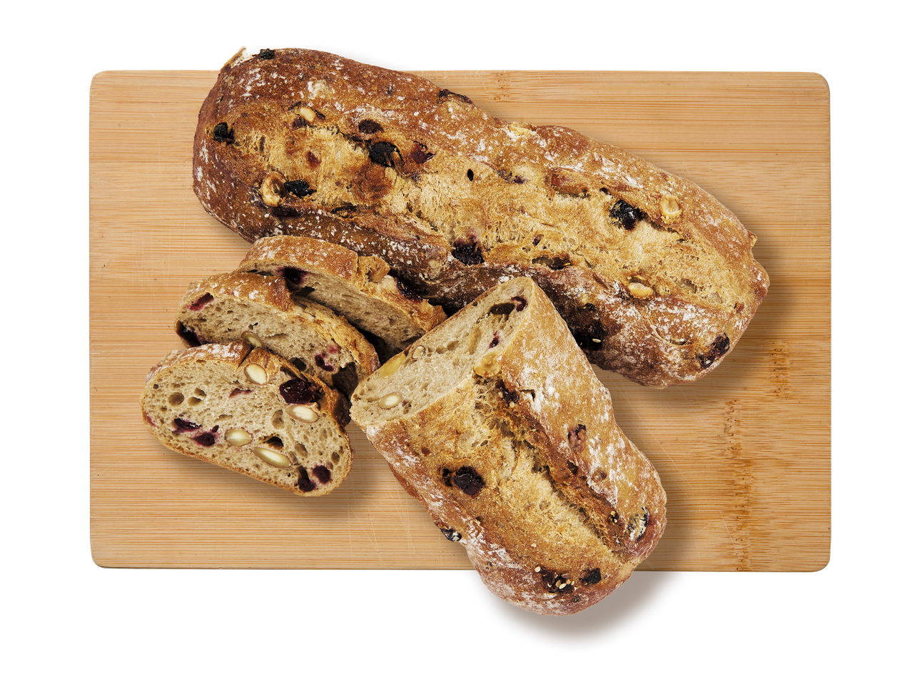 Pain aux fruits secs et aux noix, entier et tranché, sur une planche à découper en bois.