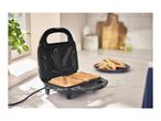 Open sandwich maker with two toasted sandwiches on a kitchen counter.