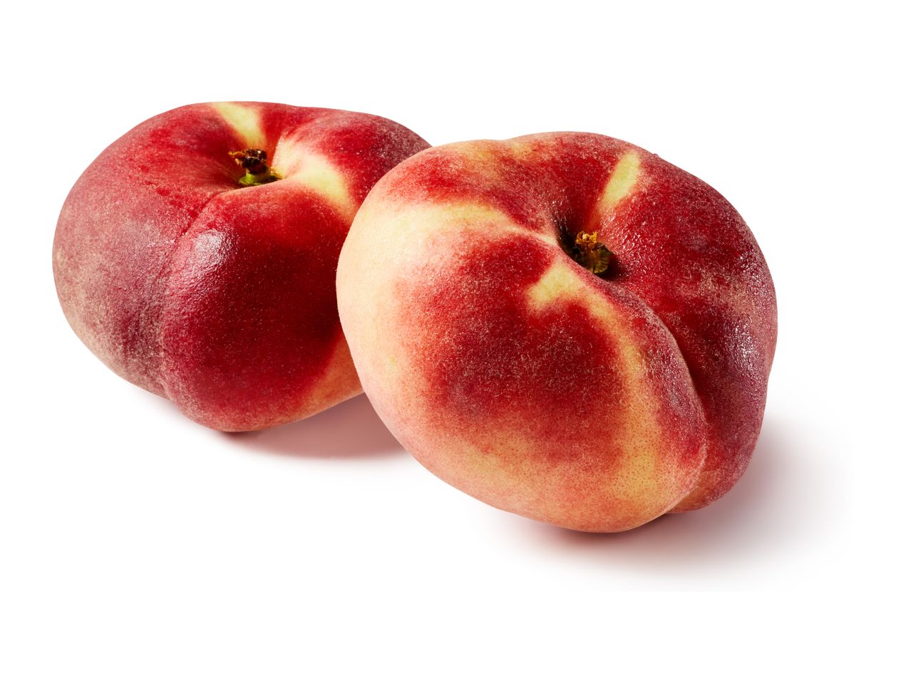 Two flat peaches with red and yellow skin, isolated on a white background.