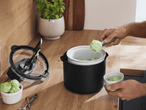 Eine Person schöpft grünes Eis aus einer Eismaschine in eine kleine Schale.