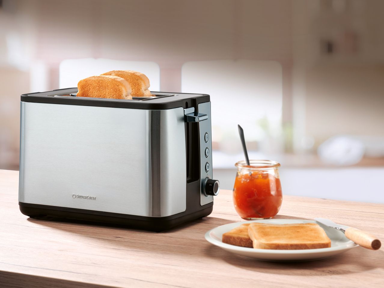 Тостер SilverCrest с препечени филийки и бурканче сладко на дървена маса.
