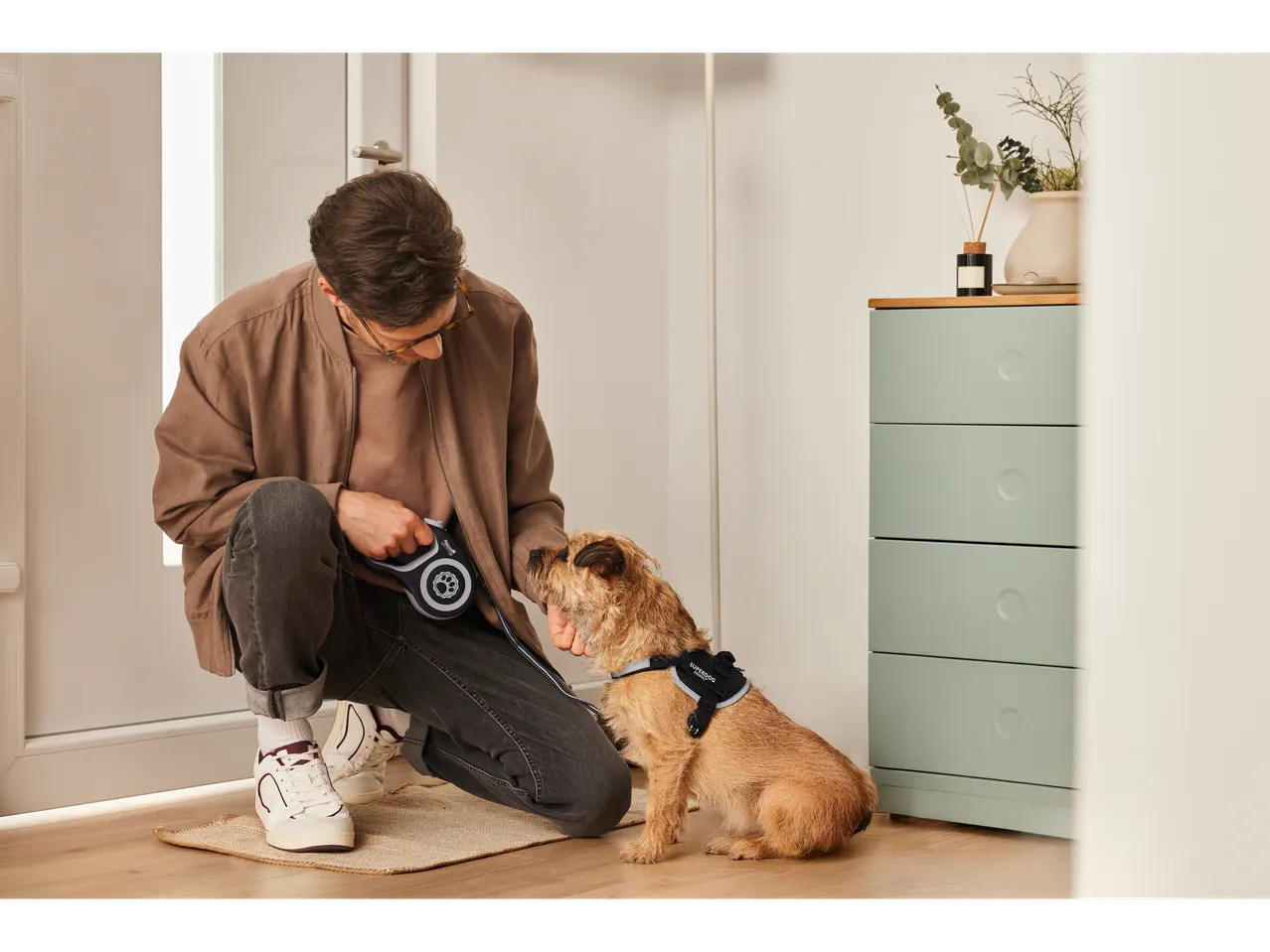 Muškarac stavlja Superdog povodac svom psu.
