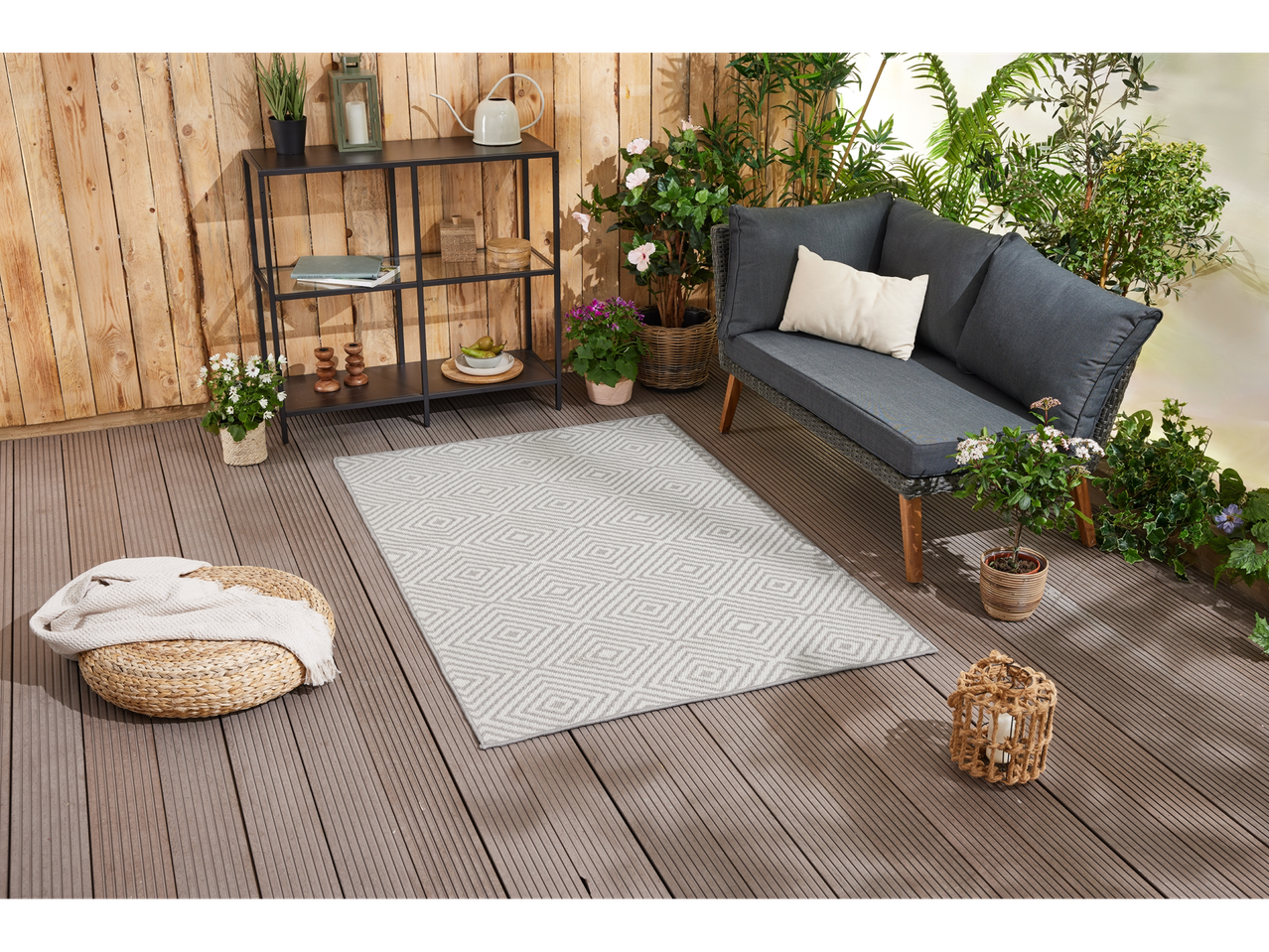 Tapis gris géométrique sur une terrasse avec un canapé et des plantes.