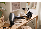 Secador de cabelo preto com difusor e escova numa casa de banho com decoração de madeira.