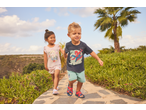 Crianças com t-shirts licenciadas do Homem-Aranha e Frozen a caminhar num caminho de pedra.