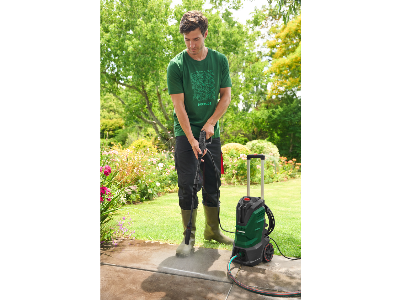 Bărbat în tricou PARKSIDE curăță o alee cu un aparat de spălat cu presiune.
