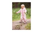 Toddler in a pink heart-patterned waterproof suit and boots splashing in a puddle.