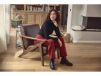 A woman in esmara® wide leg trousers and a black turtleneck sits in a living room.