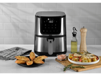 Fritadeira de ar de aço inoxidável com display digital, cercada por alimentos e utensílios de cozinha.