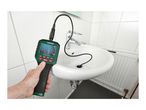 Hand holding an inspection camera with its flexible probe inserted into a bathroom sink drain.