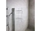 A chrome two-tiered shower Rack is mounted on a bathroom wall.