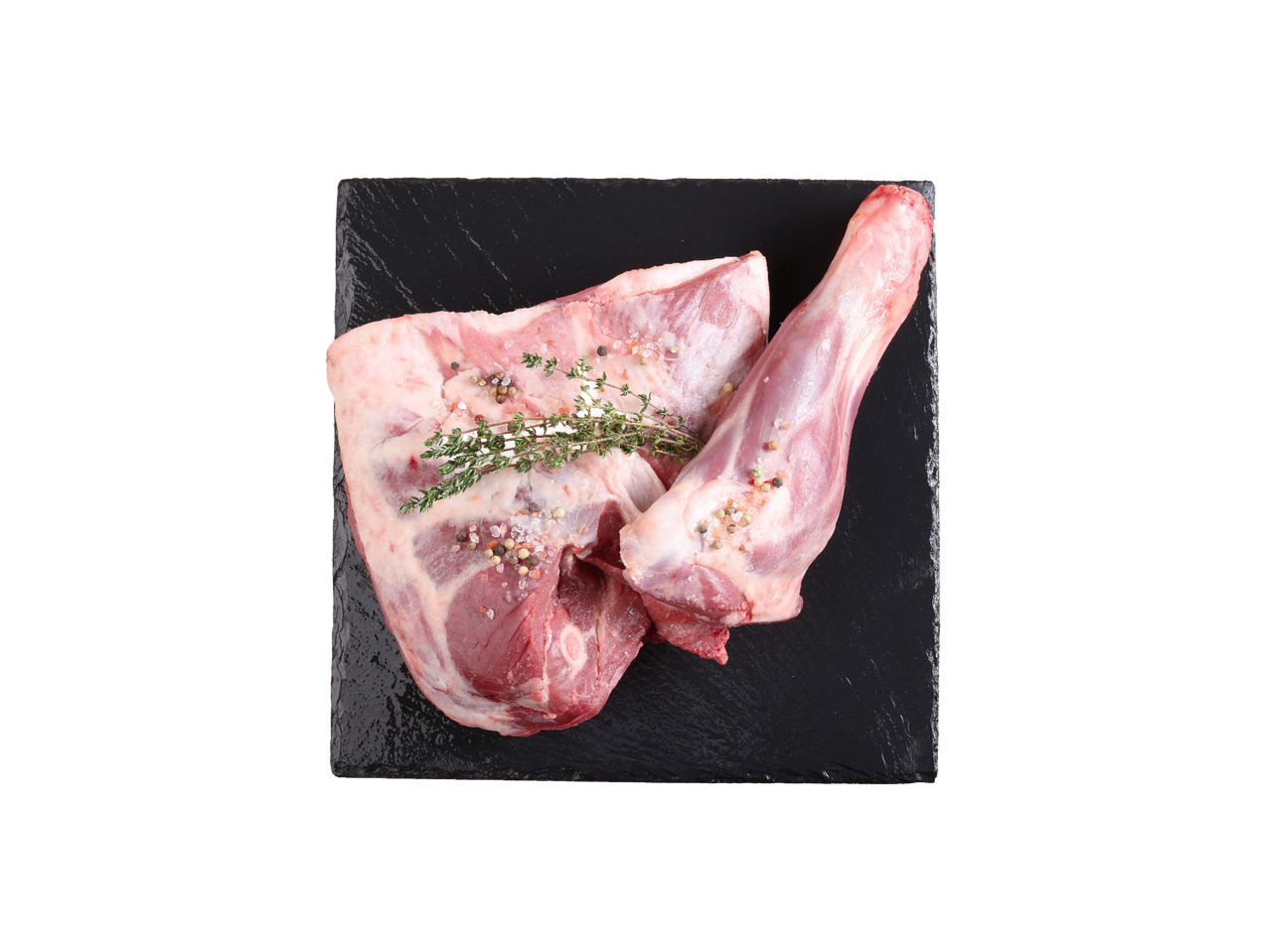 Sveža jagnjeća plećka i but sa začinima na crnoj ploči.