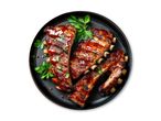 Grillede spareribs med barbecuesauce og persille på en sort tallerken.