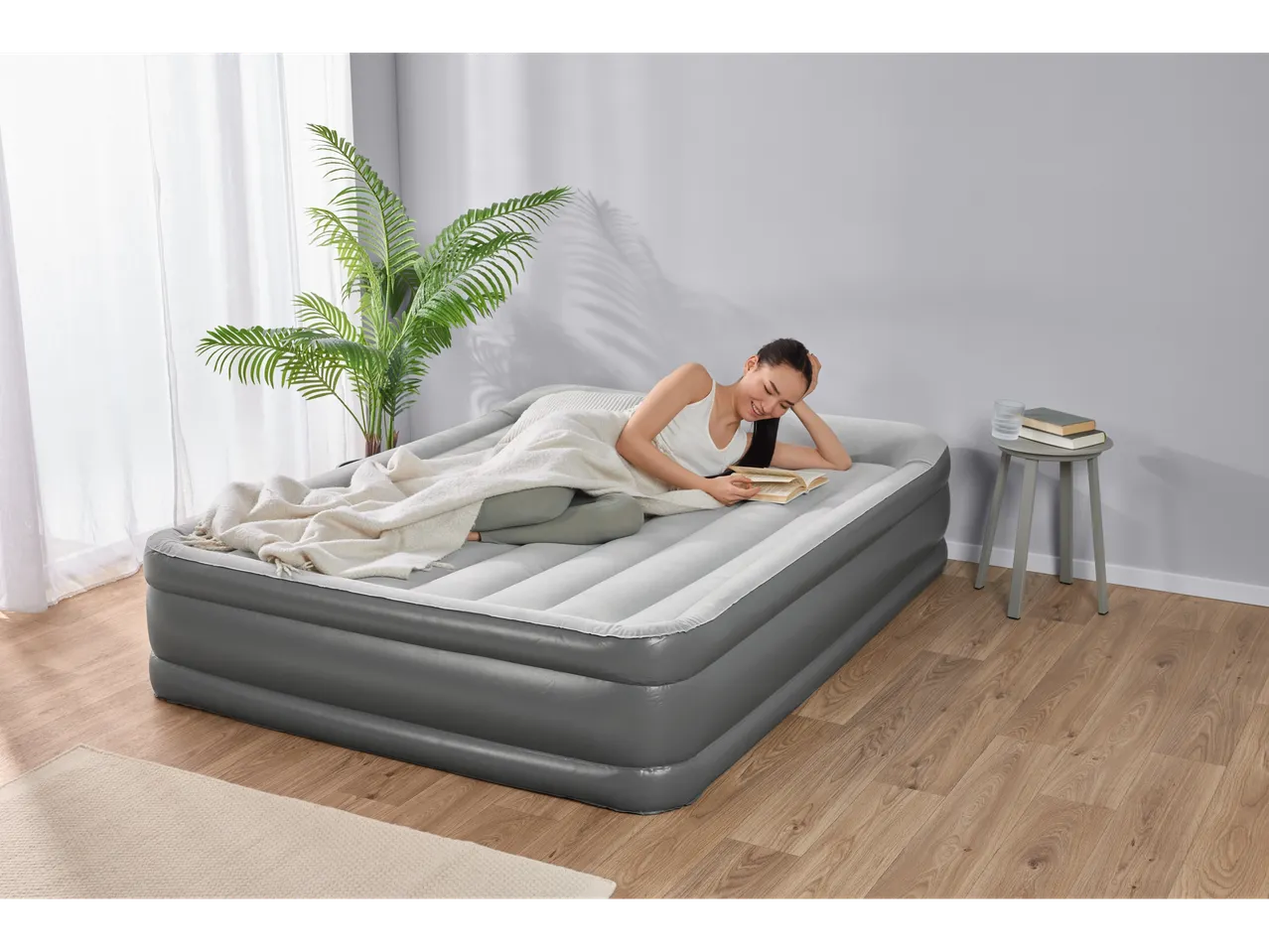 A woman relaxes on a gray Intex air mattress, reading a book.