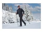 A man in a black winter jacket and trousers hiking in the snow with trekking poles.