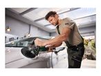 Man polishing a white car with an electric polisher in a garage.