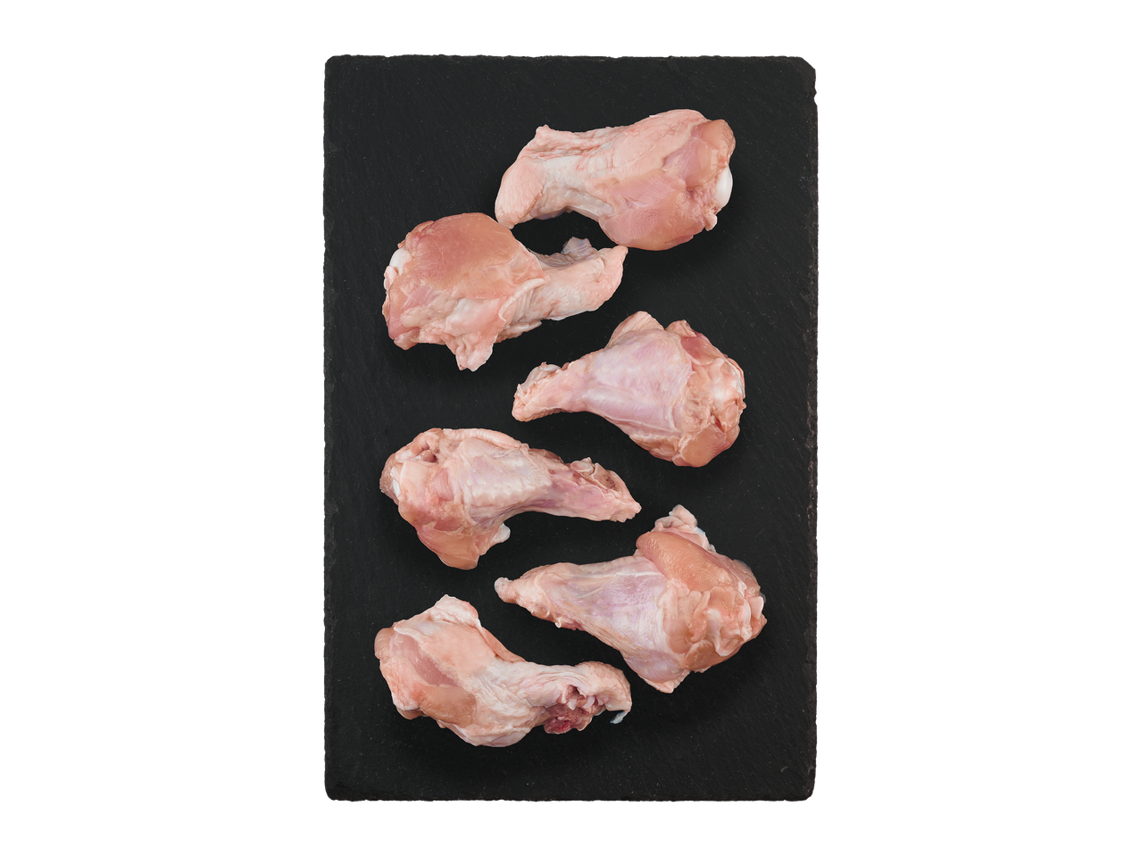 Šešios žalios vištienos blauzdelės ant juodos skalūno lentos.