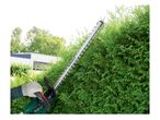 Electric hedge trimmer cutting a hedge.