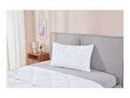 White quilted pillow and duvet on a bed with a grey headboard and a bedside table.