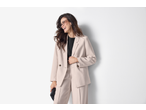 Mulher de blazer e calças bege a condizer da ESMARA, a sorrir.
