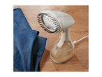 Handheld garment steamer with a brush attachment next to blue jeans on a wooden surface.