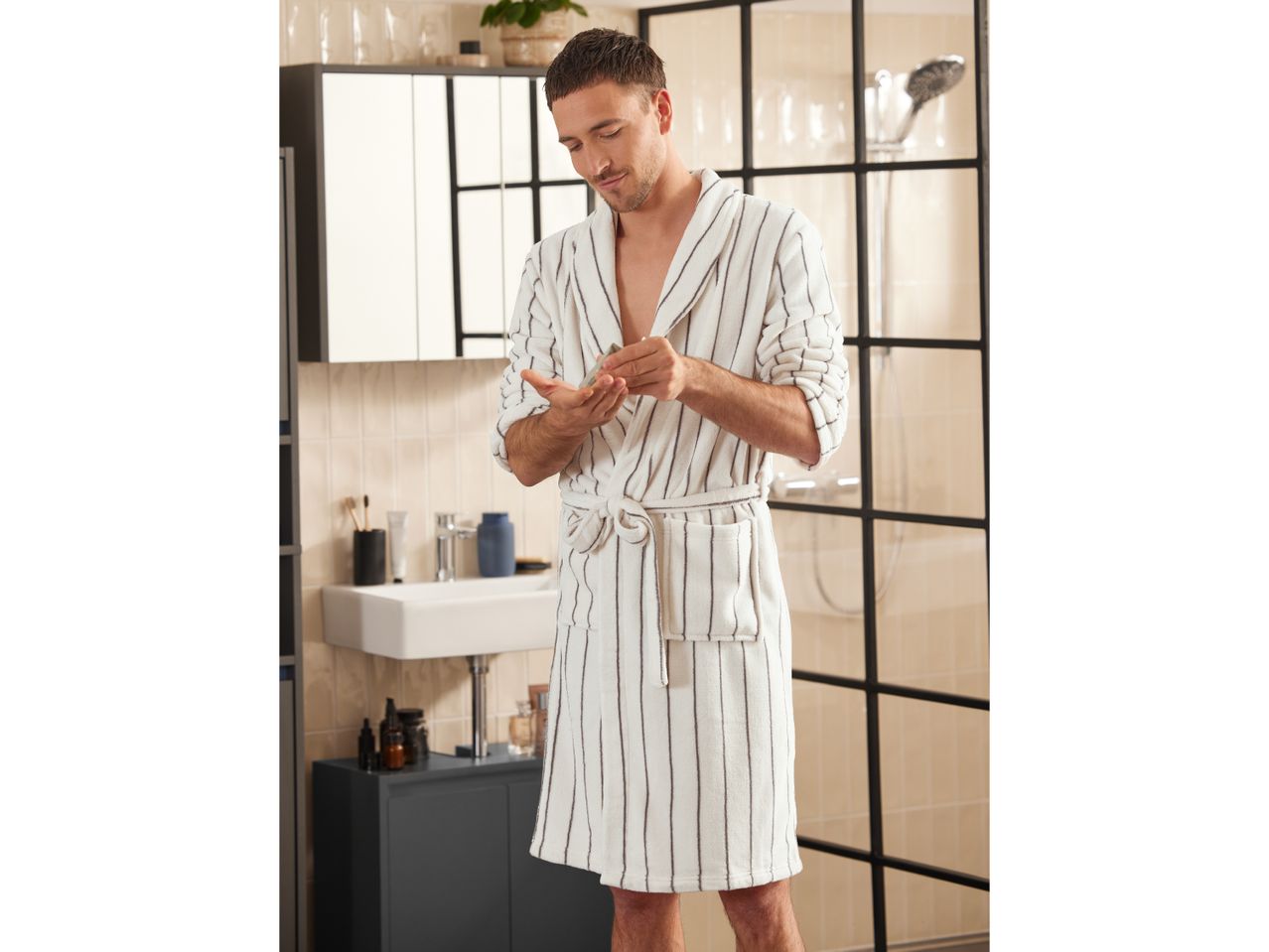 Man wearing a striped white bathrobe in a bathroom.