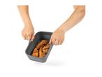 Hands holding a grey silicone air fryer basket filled with crispy chicken tenders