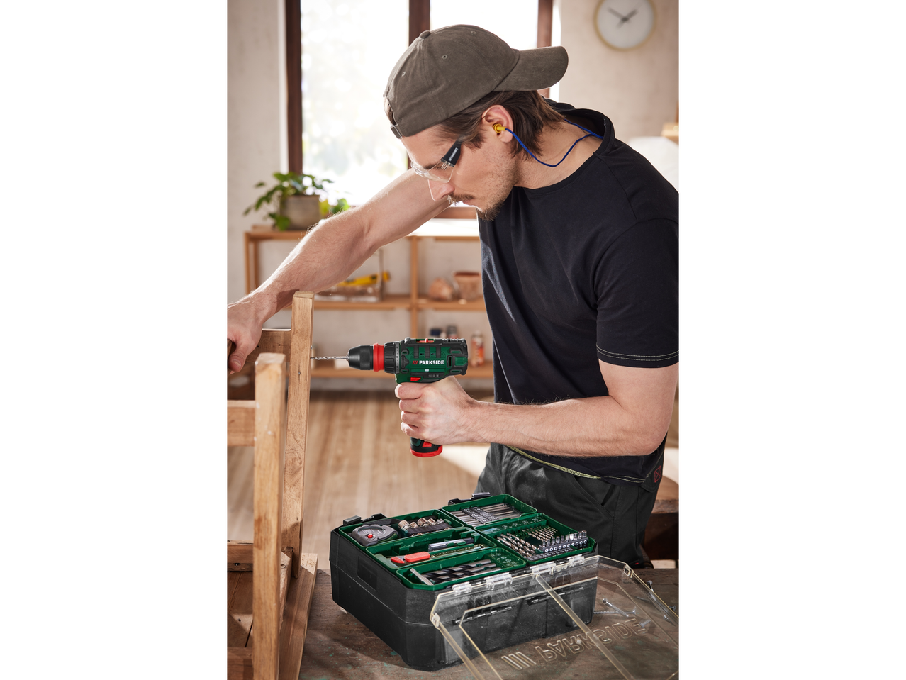 Moški uporablja Parkside brezžični vrtalnik in komplet dodatkov za DIY projekt.