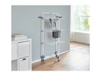A white and blue clothes drying rack with clothes on it, next to a white storage unit.