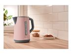 A pink SilverCrest electric kettle on a wooden kitchen counter with cookies and sugar.